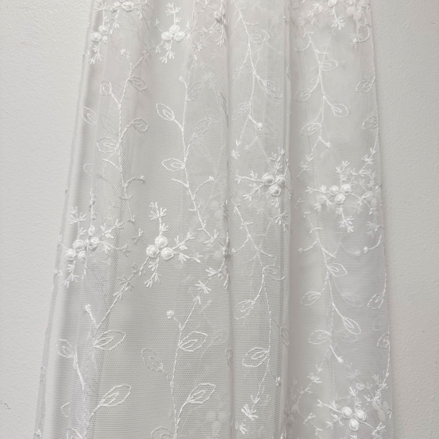 Tüllkardinakangas valge,  valge tikandiga. Aluäär sakiline, kõrgus 300cm;